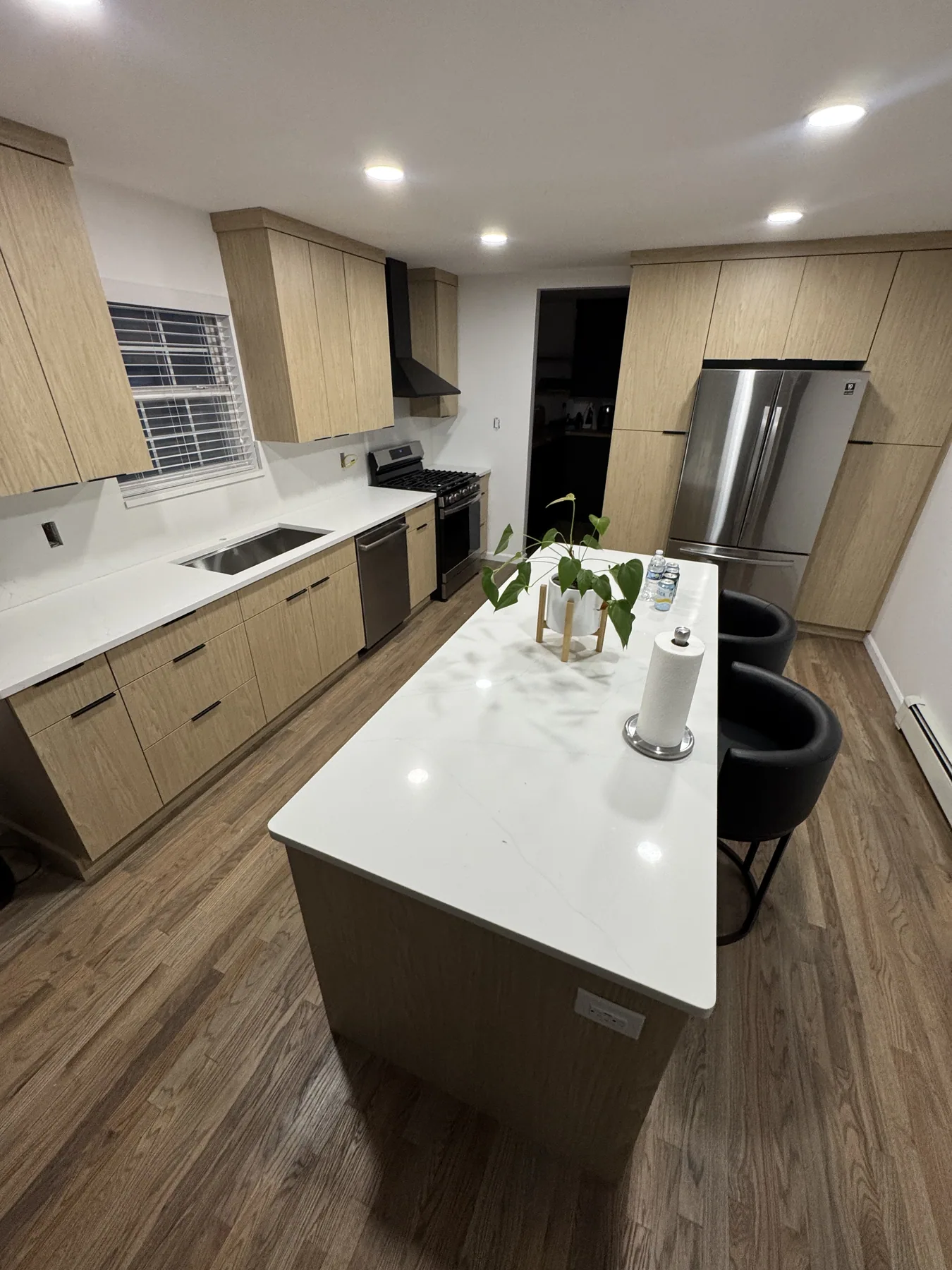 Light wood kitchen cabinets with a white waterfall-edge island countertop