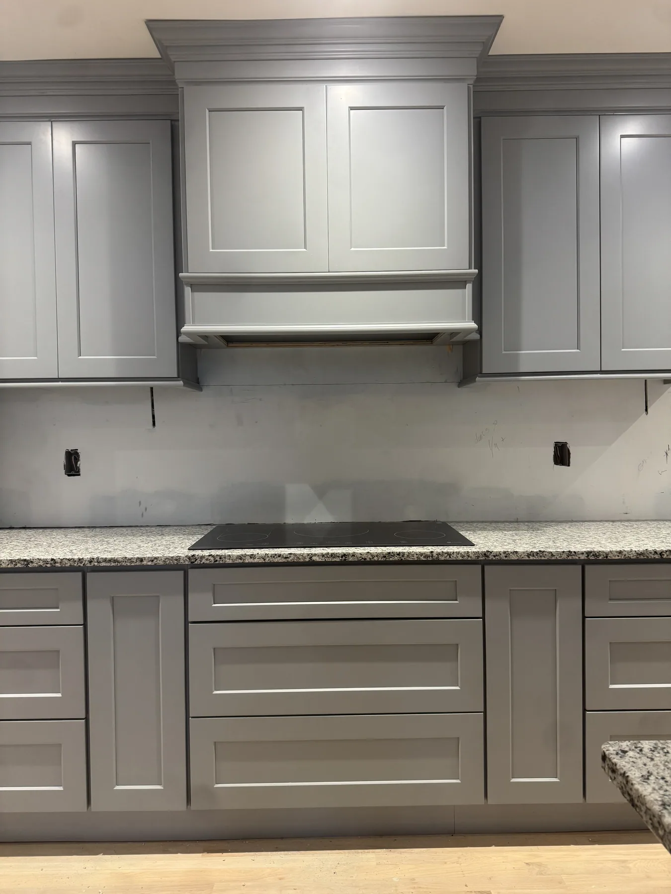 Detail of gray shaker cabinet doors beneath a granite countertop