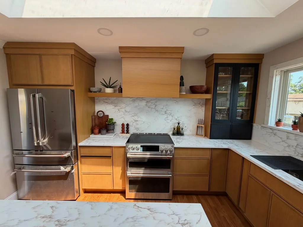 Warm wood kitchen with stainless refrigerator, double oven range and marble backsplash