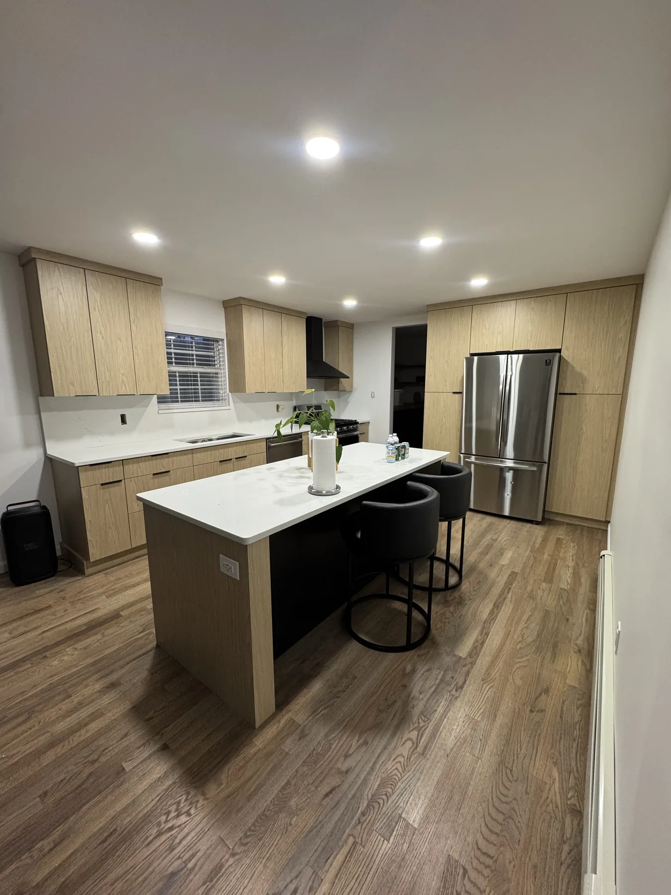 Natural wood kitchen island with white countertop and black counter stools