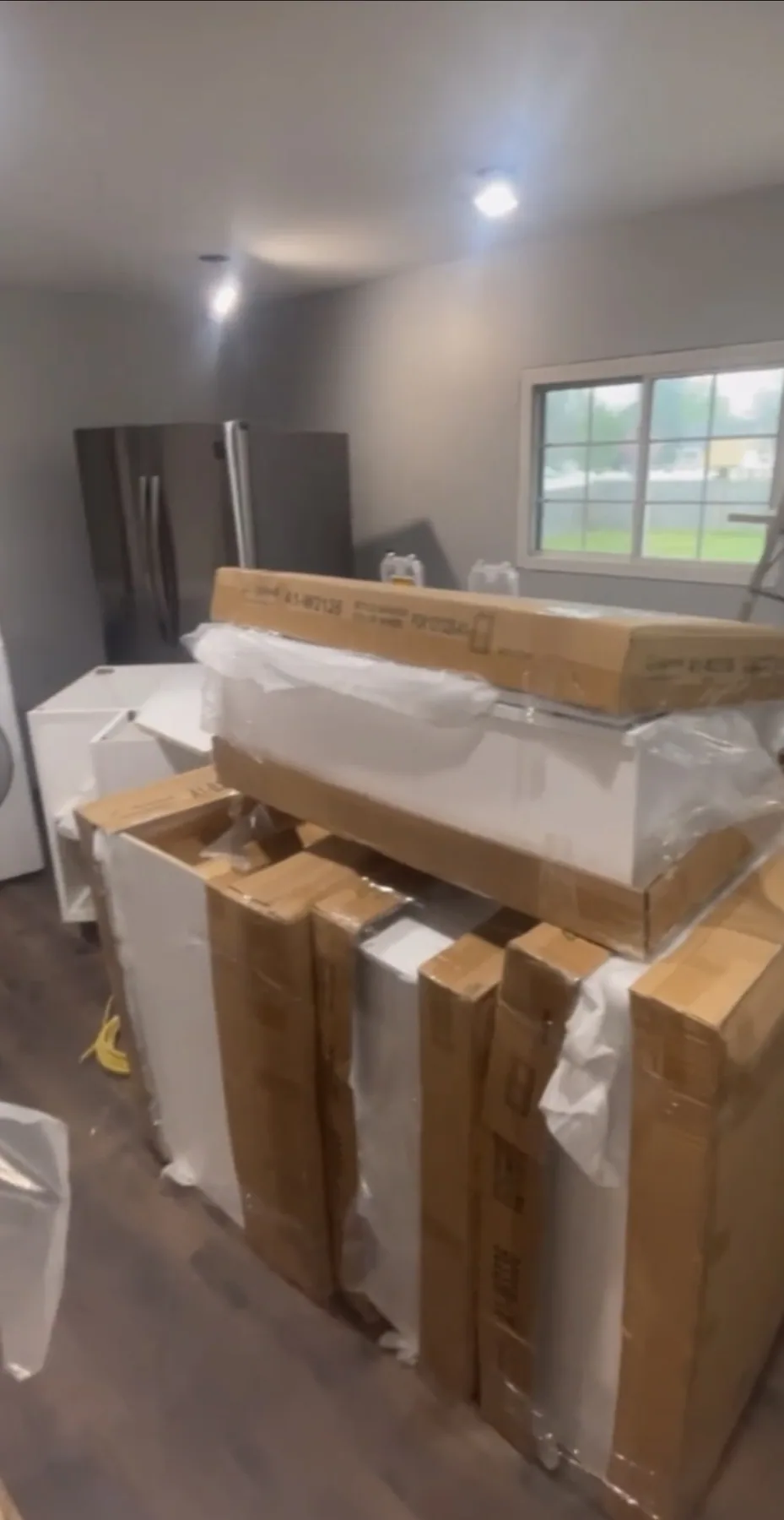 Wrapped and boxed cabinetry and project materials stacked at an installation site