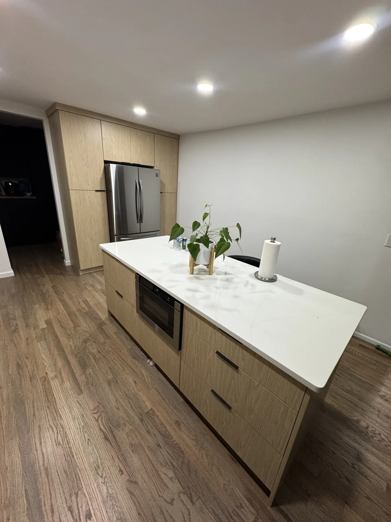 Natural wood kitchen island with white countertop and stainless refrigerator