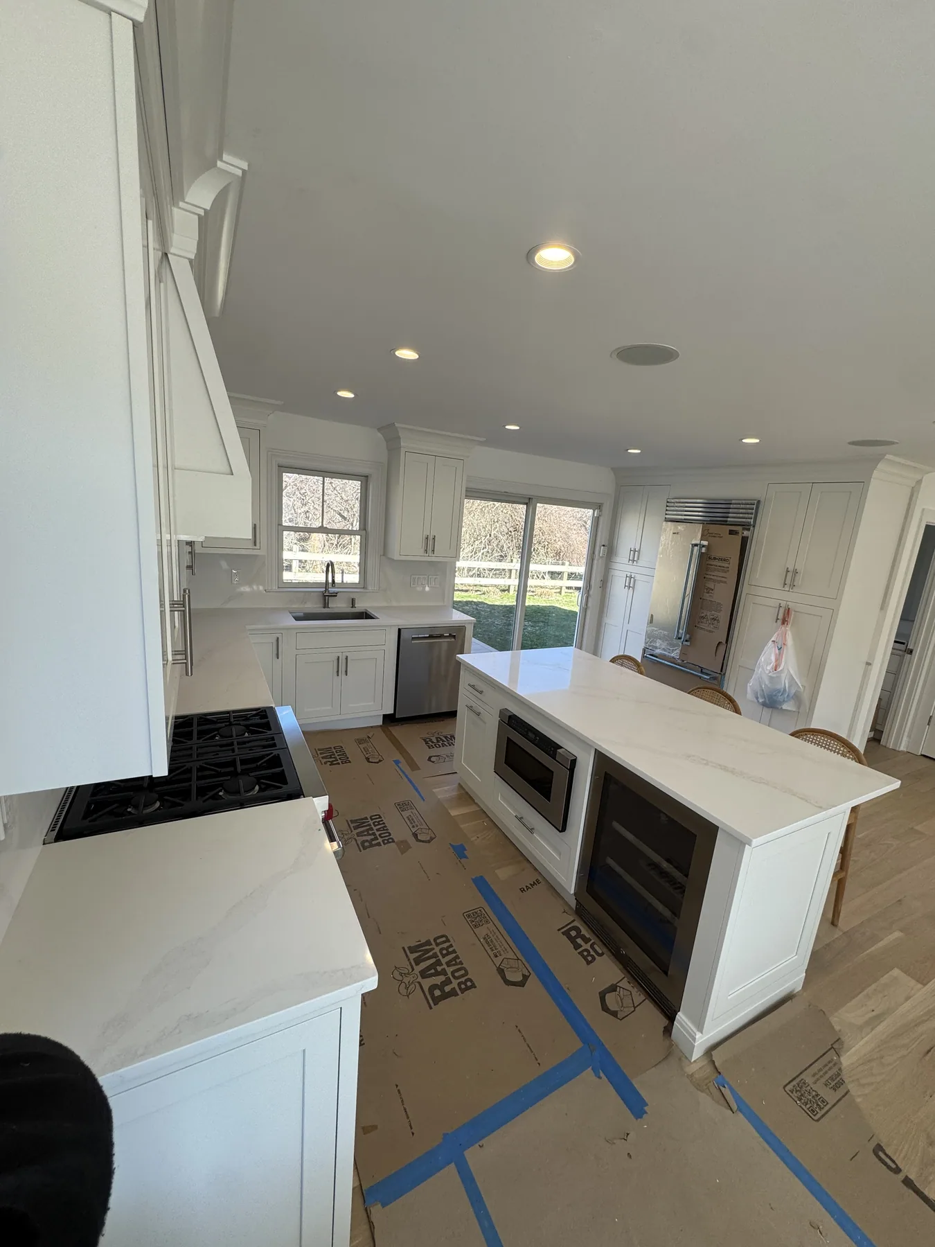 White kitchen island with marble countertop beside built-in appliances