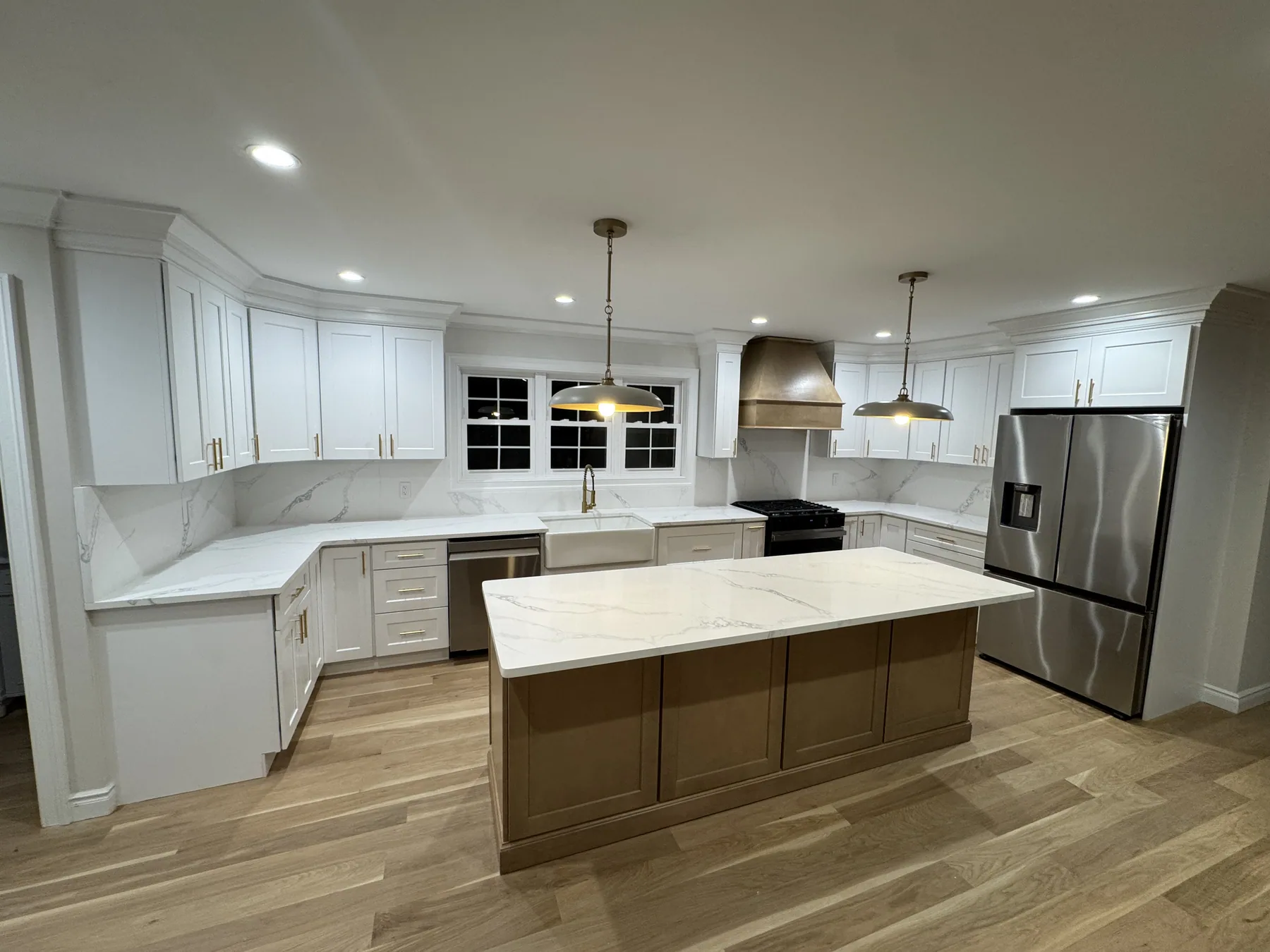 Completed white kitchen cabinets with a warm wood island and stone countertops