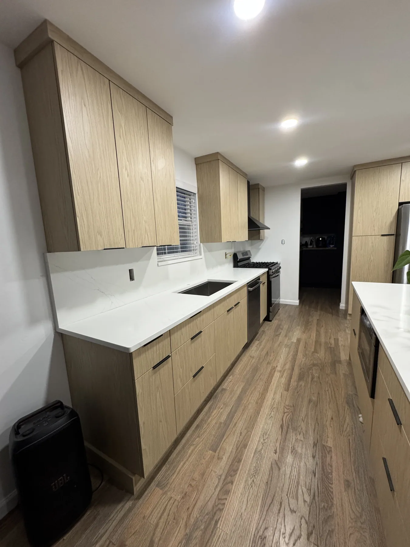 Natural wood kitchen cabinet run with white quartz countertops