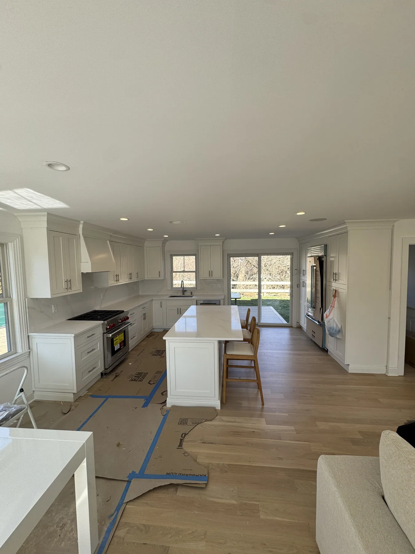 Open bright white kitchen with a marble island and wide plank wood floors