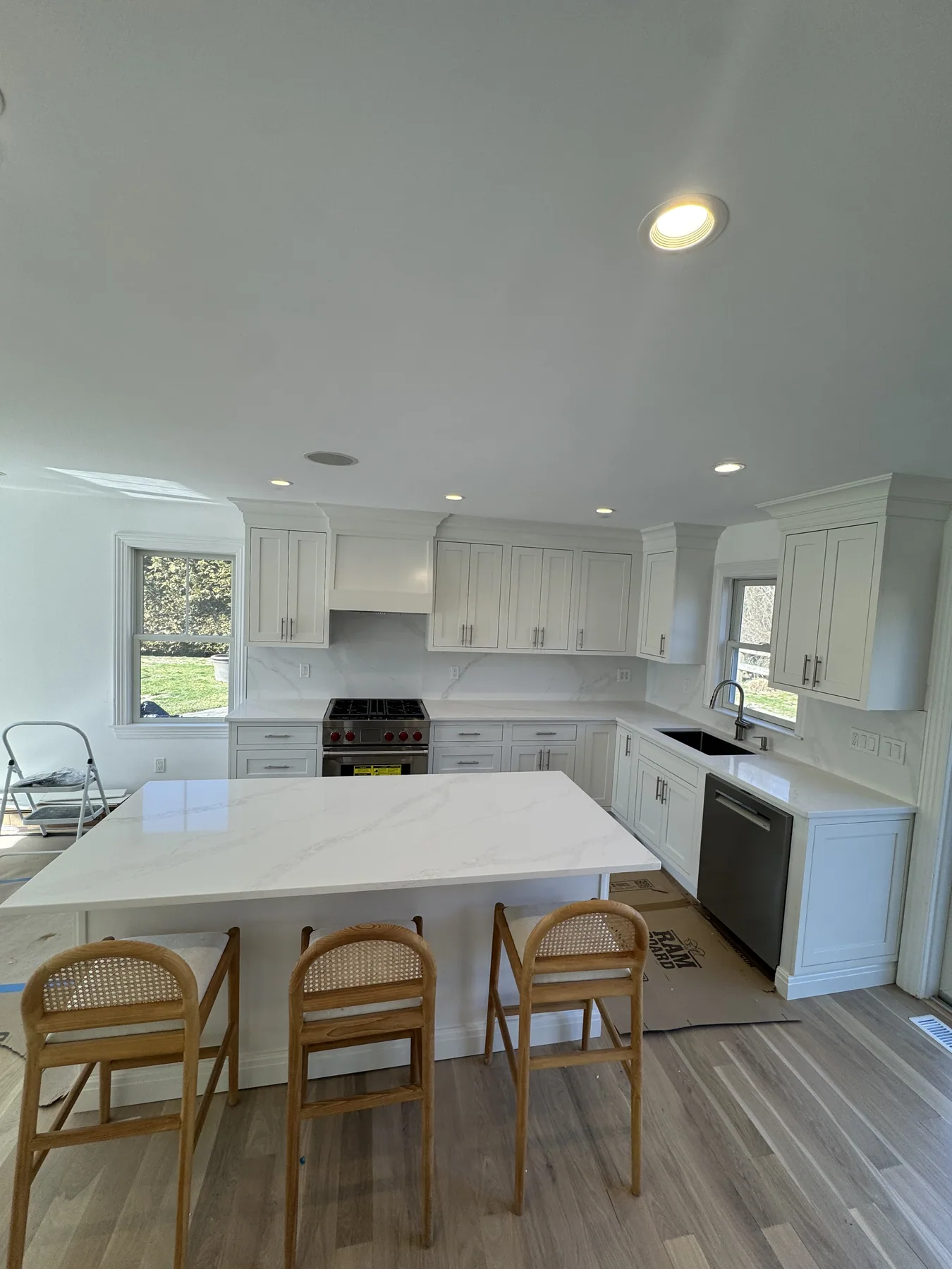 Finished bright white kitchen with marble island and rattan counter stools